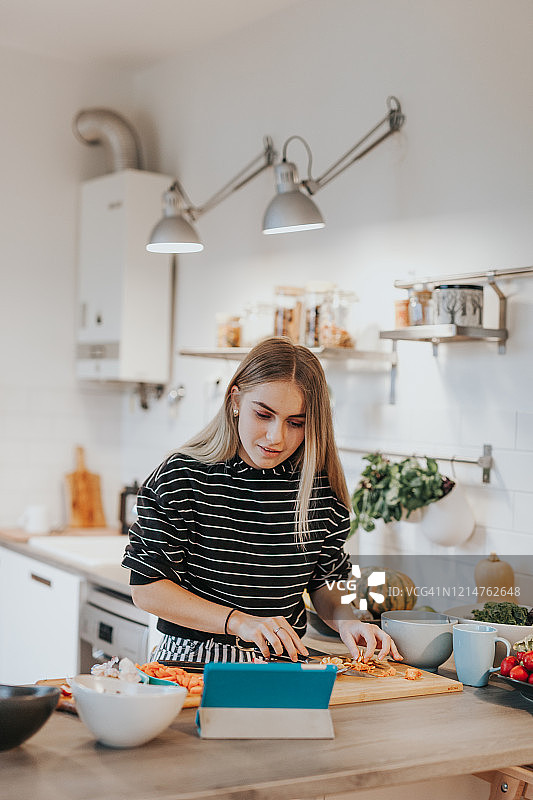 可爱的少女观看平板上的烹饪视频学习烹饪素食图片素材