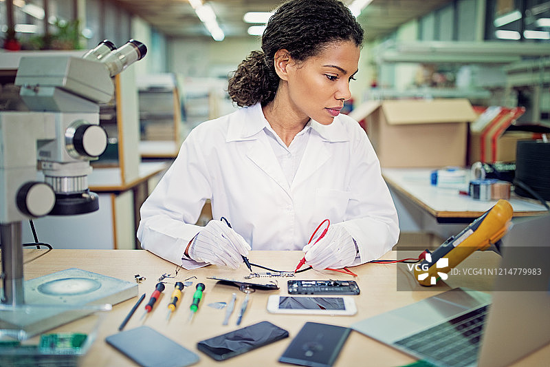 年轻女人在维修店修理手机图片素材