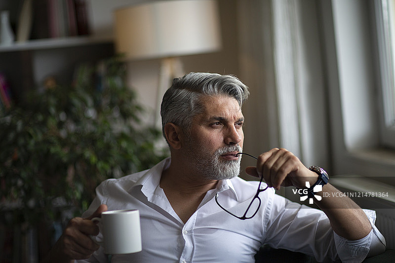 一位坐在沙发上喝咖啡的商人肖像图片素材