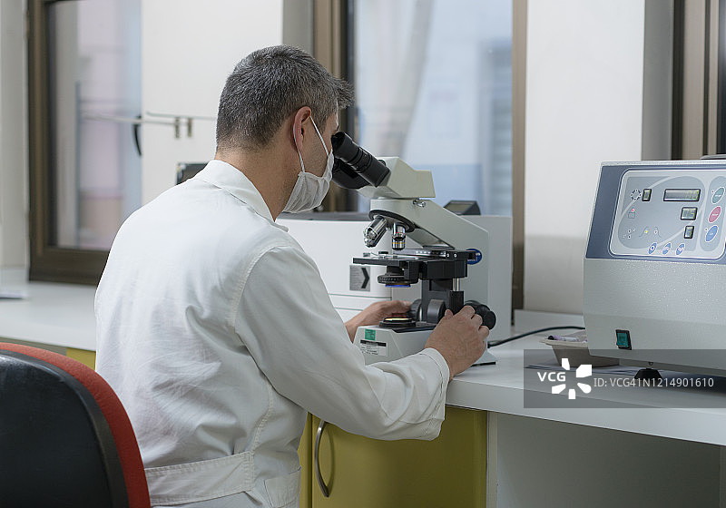 男科学家坐在现代实验室里，观察显微镜图片素材