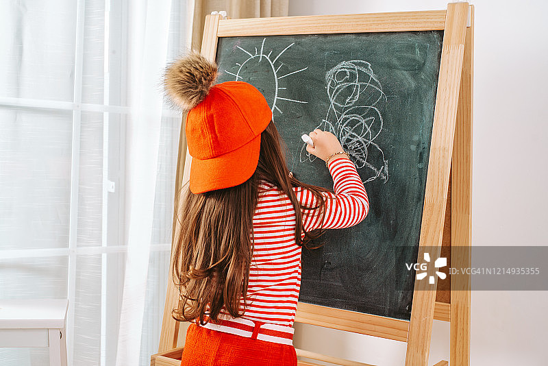 小女孩在黑板上画画图片素材