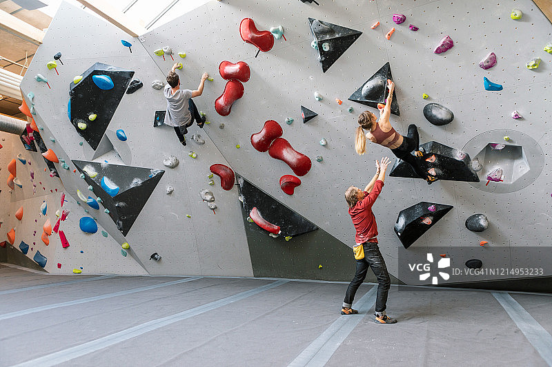 健身房里，男教练指导一男一女攀岩图片素材