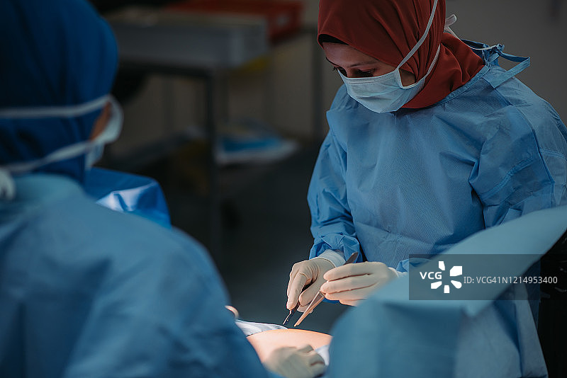 亚洲马来西亚女外科医生团队在医院手术室为华人老年妇女进行腹部手术图片素材
