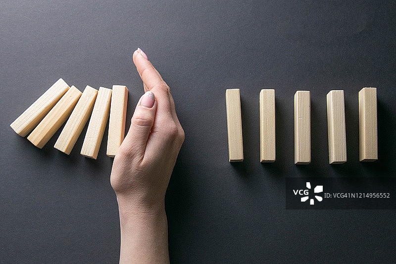 阻止多米诺骨牌倒塌的手，商业危机管理概念图图片素材
