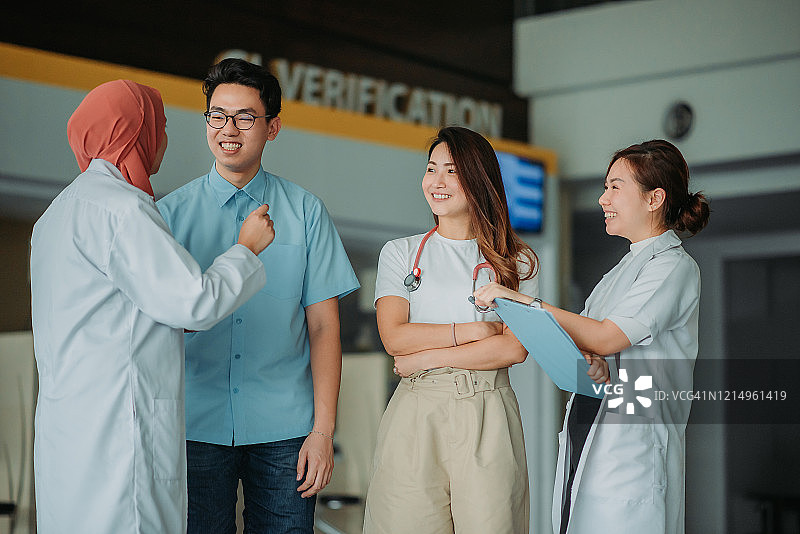 一群亚洲多民族医生在医院大厅微笑讨论图片素材