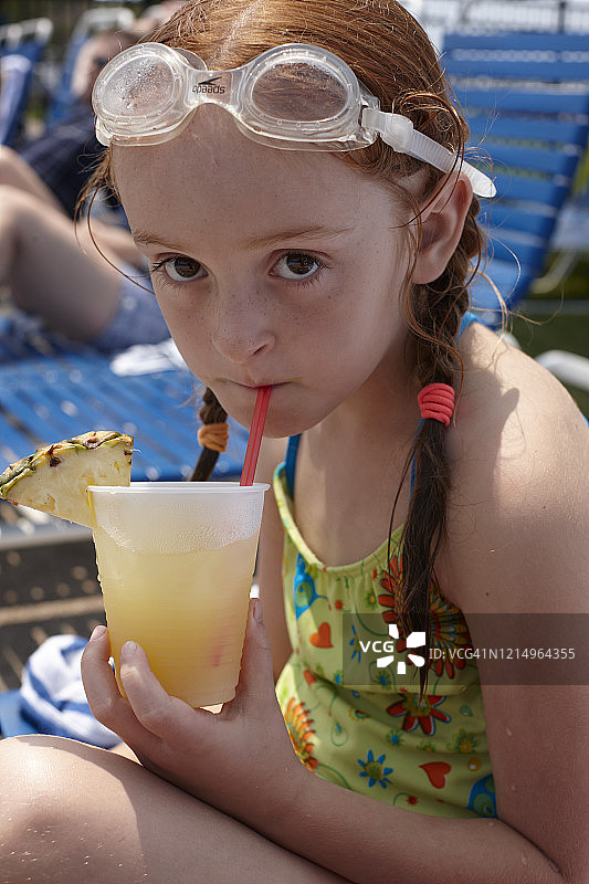 红发年轻女孩戴着护目镜喝冰冻鸡尾酒图片素材