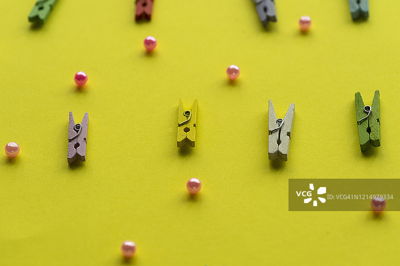 黄色背景上的彩色衣夹和珍珠特写图片素材