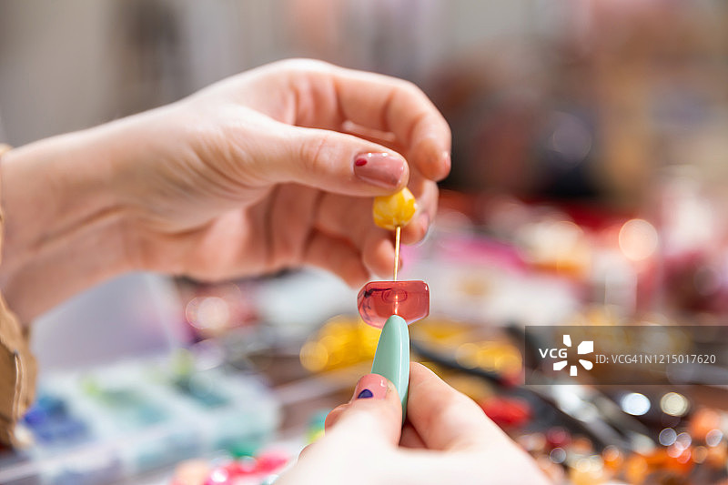 女模特在工作台上使用珠子、钳子和其他工具制作珠宝图片素材