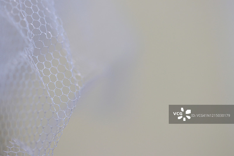 奶油色背景下的白色薄纱面料特写镜头图片素材