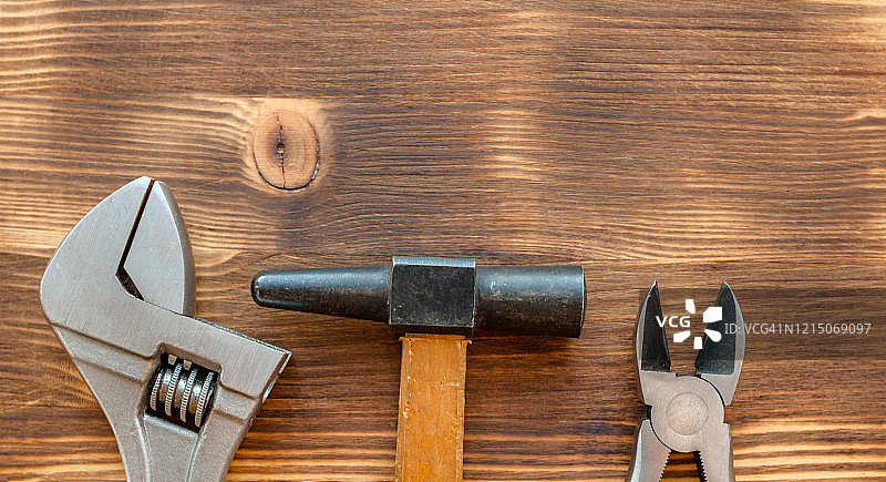 棕色木质背景上的旧维修工具：锤子、钳子、扳手，劳动节概念图片素材
