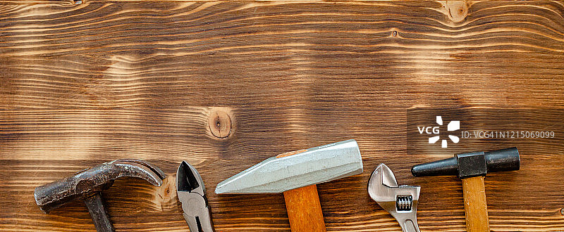 棕色木质背景上的旧维修工具：锤子、钳子、扳手，劳动节概念图片素材