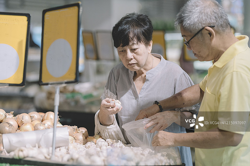 在超市水果区挑选洋葱的亚洲老年夫妇图片素材