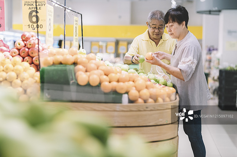 中国老年夫妇在超市水果区选购苹果图片素材