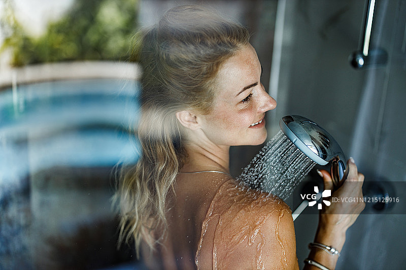 在浴室淋浴的快乐年轻女人图片素材