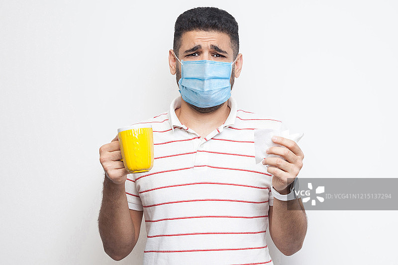 不开心生病的男人戴口罩喝热茶图片素材