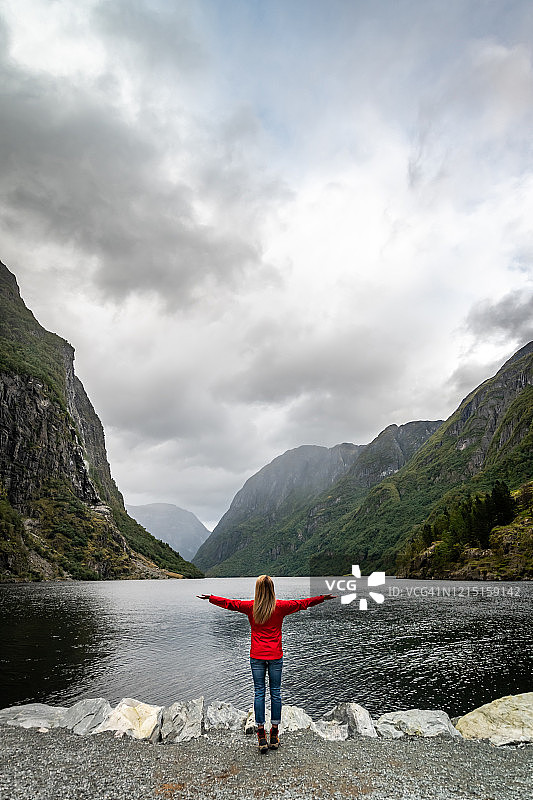 看向峡湾和山脉的女人图片素材