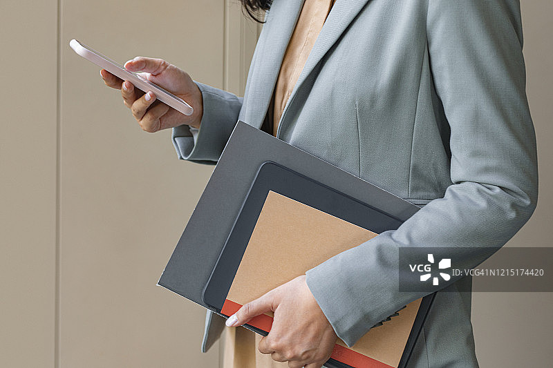 拿着文件在智能手机上发短信的身份不明女商人局部照片图片素材