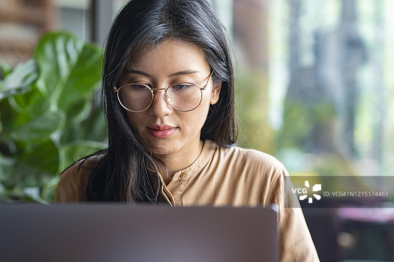 自由职业：亚洲女性在咖啡馆使用笔记本电脑工作特写图片素材