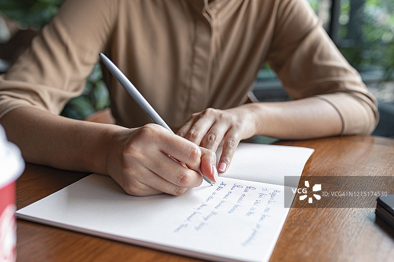 提前计划：匿名女性在笔记本上写笔记的裁剪照片图片素材