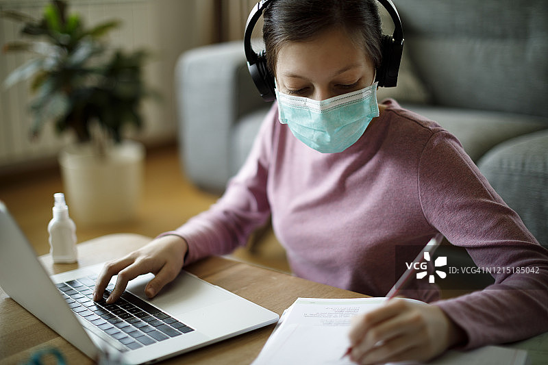 戴着防护口罩在家学习的少女学生图片素材