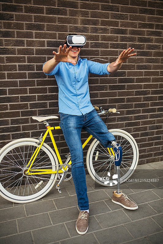 戴着VR眼镜玩游戏的装有假肢的年轻男子图片素材