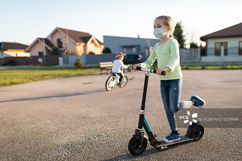 戴防护面罩的小孩骑滑板车图片素材