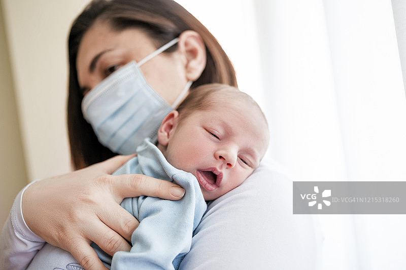 戴着防护口罩的母亲抱着肩膀上的宝宝，宝宝睡着了图片素材