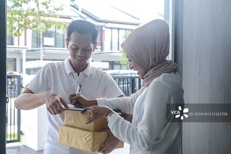 快递员给年轻的穆斯林女子送货图片素材
