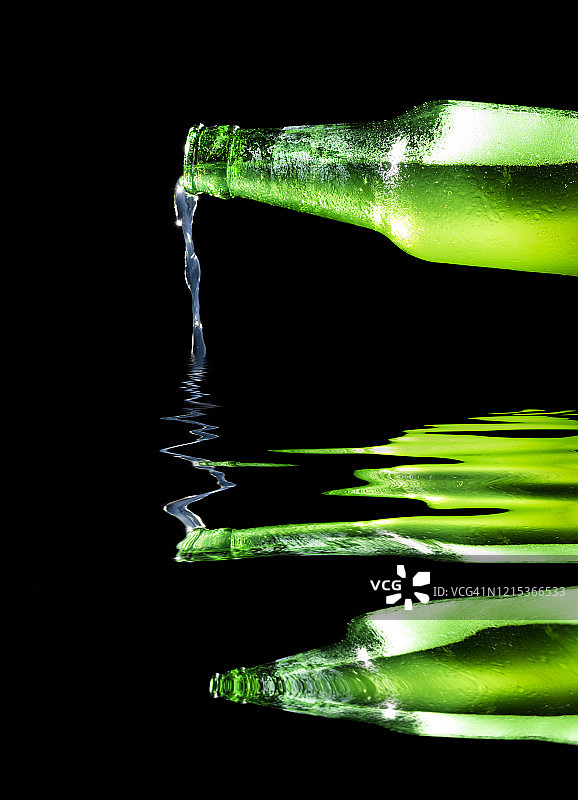 黑色背景下水中倒影的柠檬汽水瓶图片素材