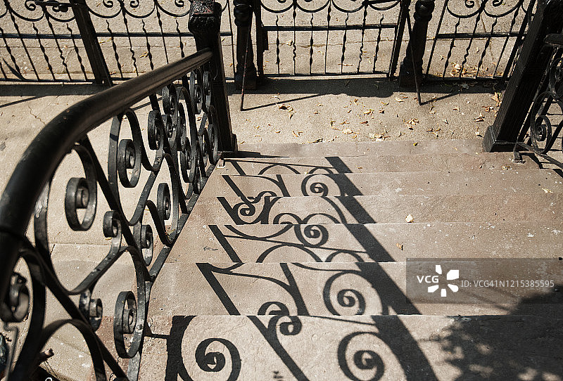 棕色砂石门廊上的锻铁栅栏阴影图片素材