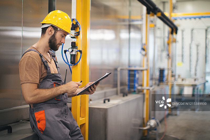 在工厂使用和检查机器的年轻男人图片素材
