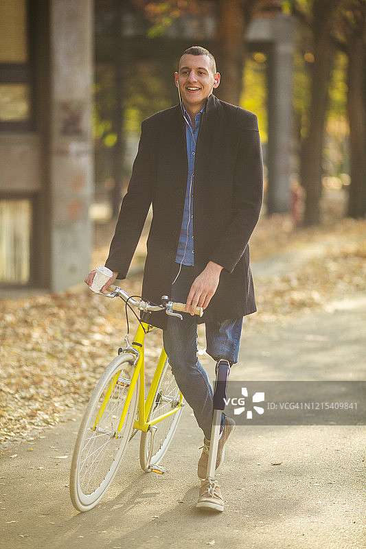 佩戴假肢的年轻男人在自行车旁行走图片素材