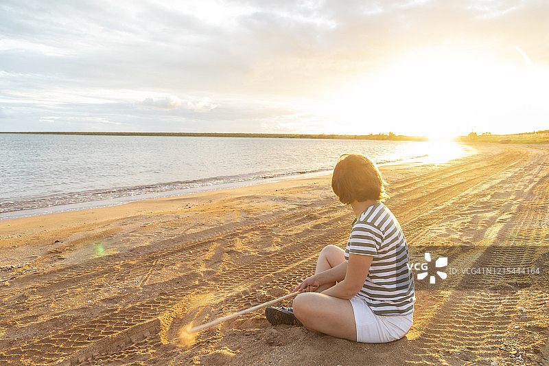 女人坐在日落的海滩上图片素材