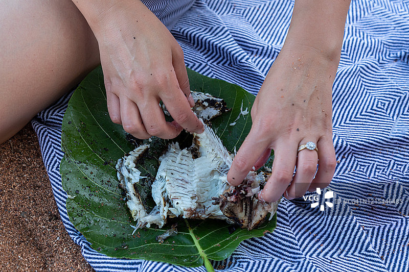 用手吃明火烹制的新鲜鱼，盛在树叶上图片素材