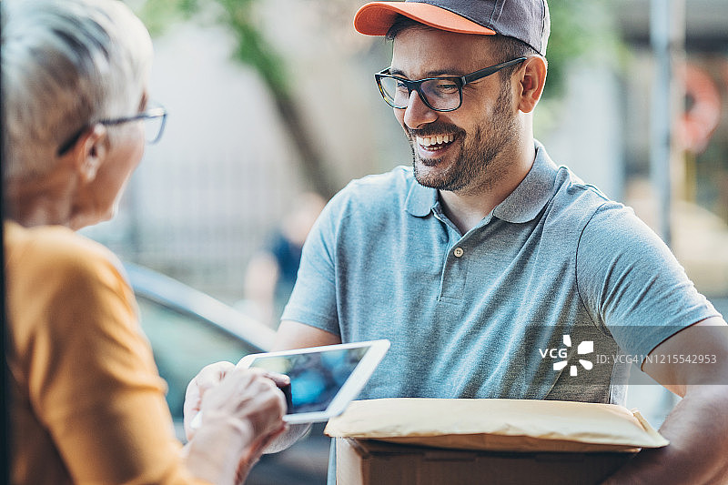 老年妇女在数字平板电脑上签名接收包裹图片素材