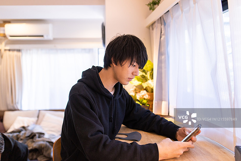 年轻男人在房间里使用智能手机图片素材