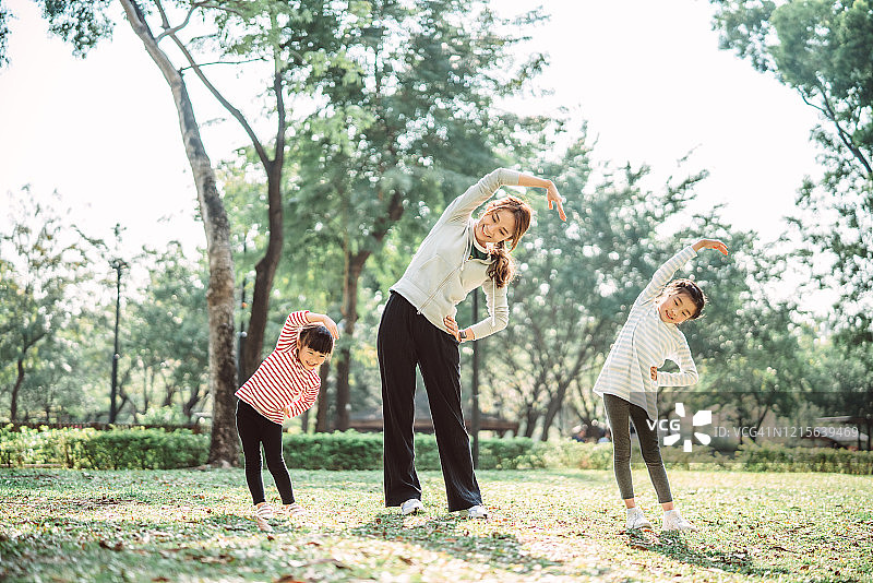 年轻家庭在草坪上愉快地做伸展运动图片素材