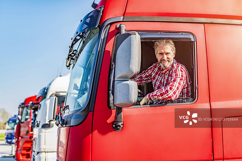 坐在停车场卡车里看着镜头的卡车司机图片素材