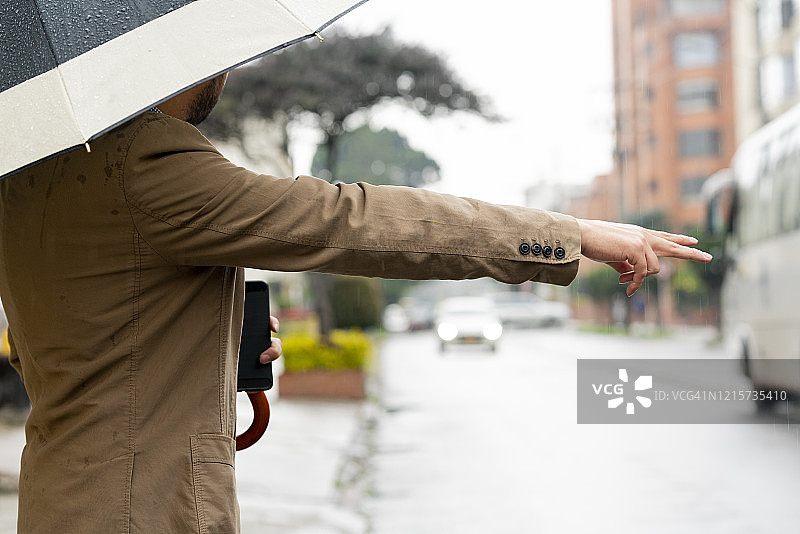 下雨天在街上等网约车的年轻男人图片素材