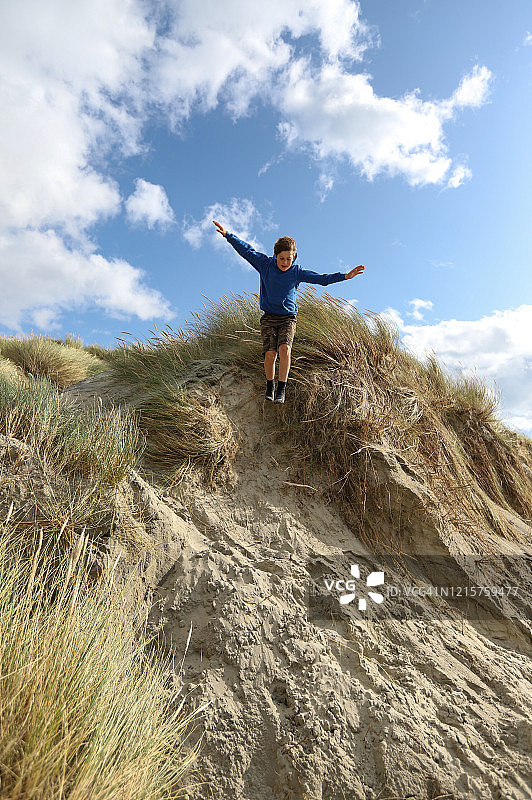 男孩从沙丘上跳下图片素材