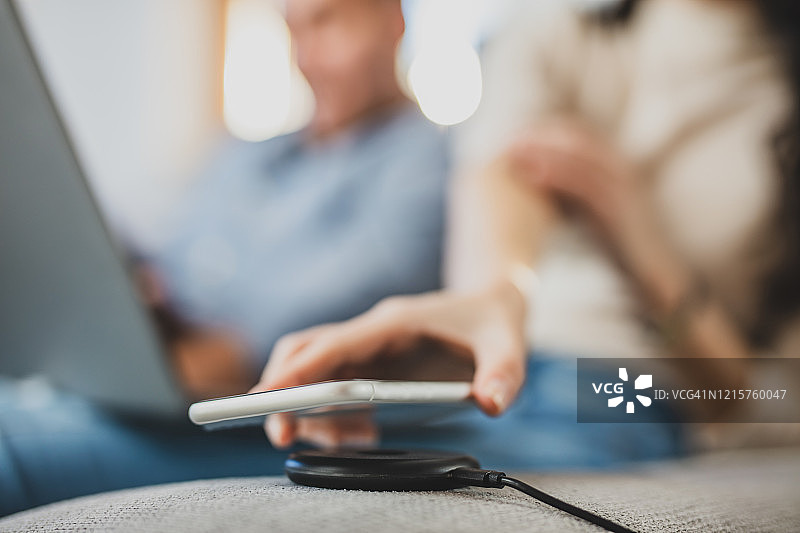 特写：女人将智能手机放在无线充电器上图片素材