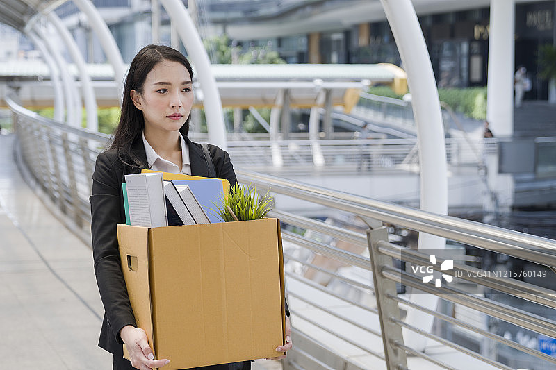 员工抱着箱子离开办公室的半身照图片素材