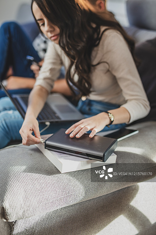 年轻女人将笔记本电脑插入充电宝图片素材