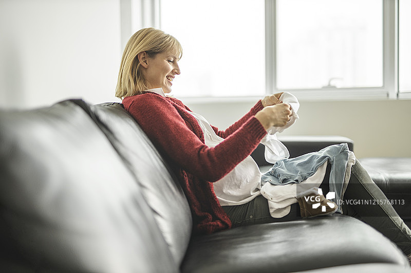 孕妇看着婴儿服装图片素材
