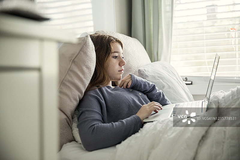 在卧室里使用笔记本电脑的少女图片素材