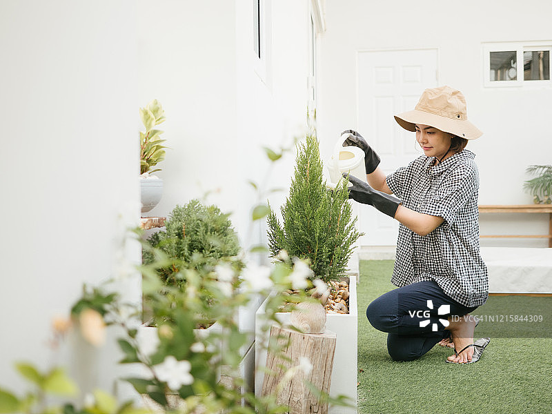 年轻亚洲女性在家中浇灌香草植物图片素材
