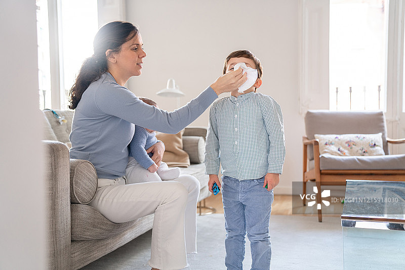 母亲帮助儿子擤鼻涕图片素材
