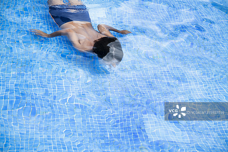 男孩在户外游泳池中跳水（高角度）图片素材