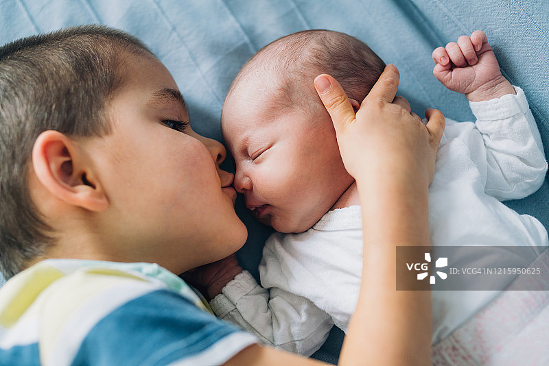 小男孩亲吻新生妹妹。图片素材