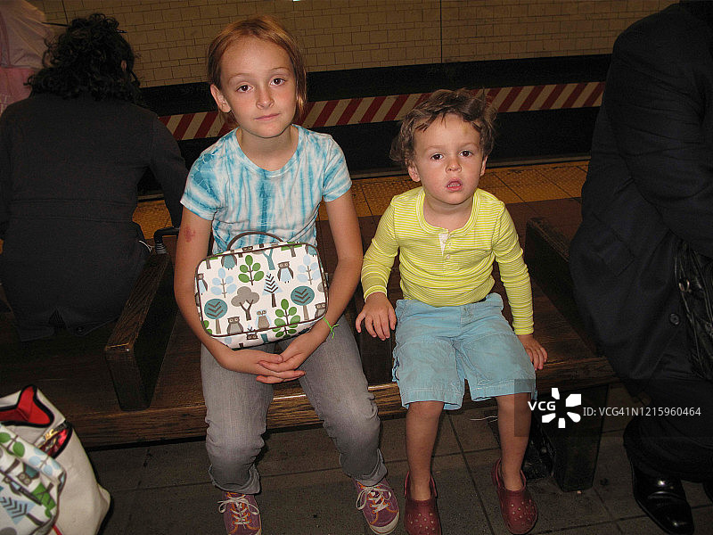 在纽约市地铁站长椅上等候火车的兄弟姐妹图片素材